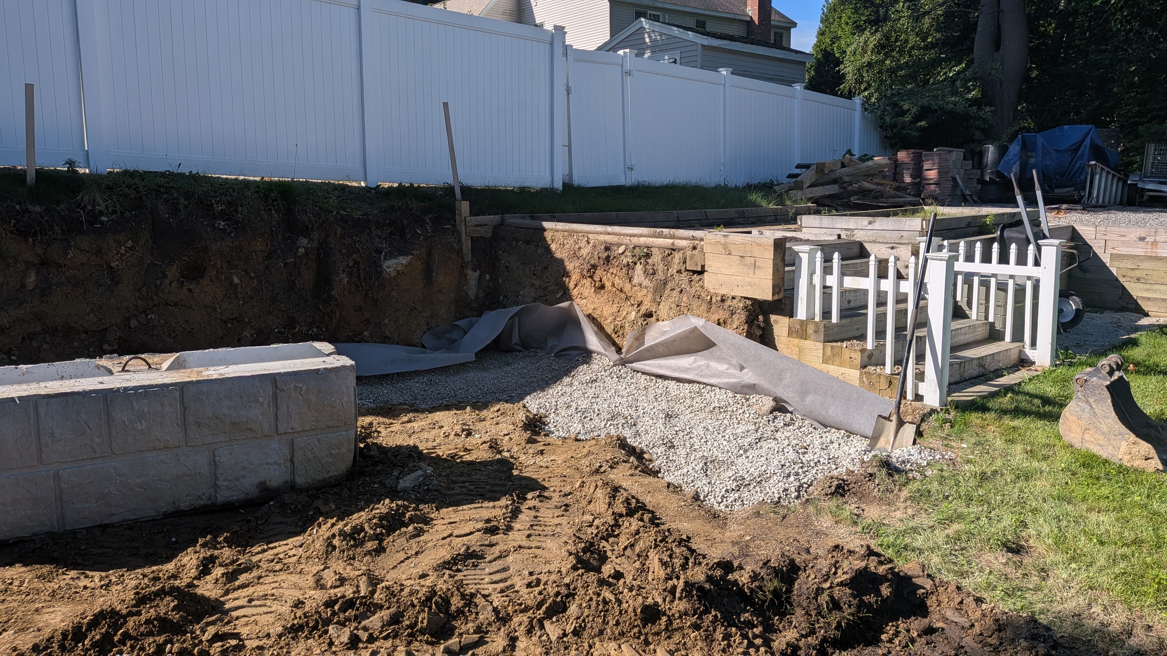 Retaining wall base with drainage stone and filter fabric during installation